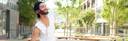 man with white sleeveless shirt wears headphone smiles looks at sky in quiet park