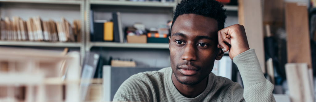 man hand on face sits alone in office room thinking