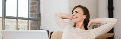 young woman sits alone in office smiles looks outside window