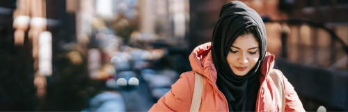 woman wears black hoodie and light pink raincoat face down walks alone