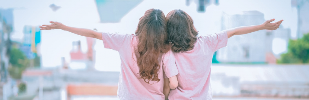 two girls face backward arms raised enjoy life