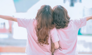 two girls face backward arms raised enjoy life