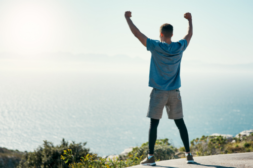 Rear view shot of a young man celebrating his victory after a run outdoors