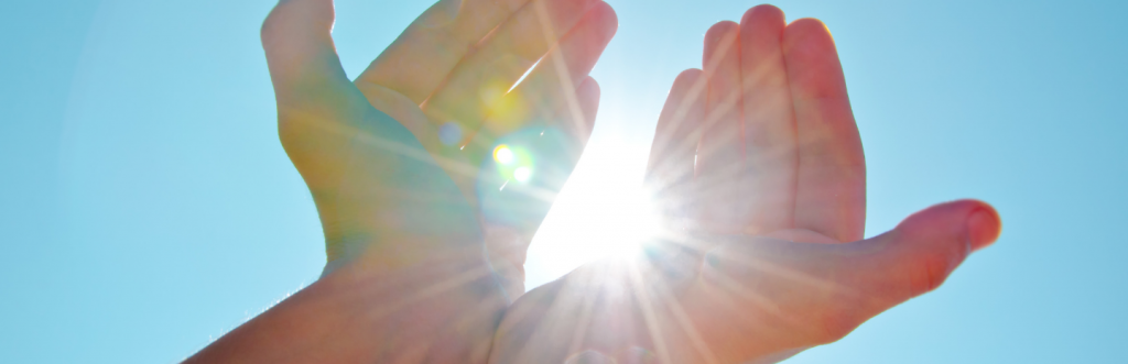 two hands cover sunlight in clear blue sky