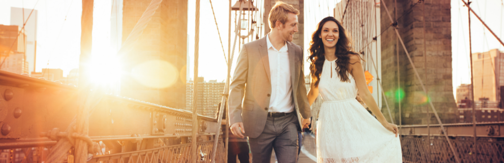 happy couple hand in hand walks along the bridge in sunny sky