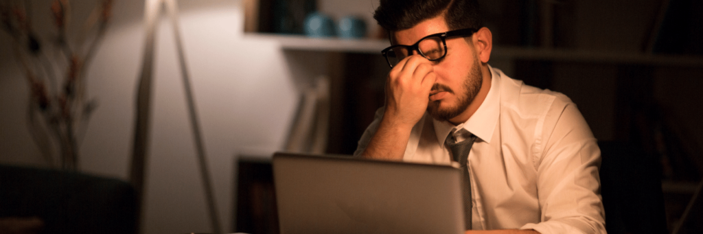 Working Man Burnout in his Career, Looking stressed in front of his laptop in an office setting.