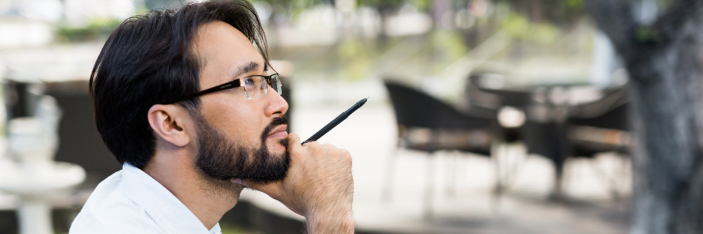 Inspired Asian man sitting in outdoor cafe