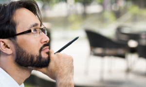 Inspired Asian man sitting in outdoor cafe