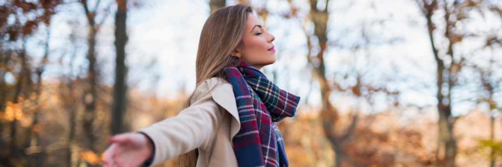 Beautiful young woman enjoying autumn idyll in the nature with her arms outstretched