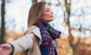 Beautiful young woman enjoying autumn idyll in the nature with her arms outstretched