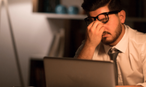 Working Man Burnout in his Career, Looking stressed in front of his laptop in an office setting.