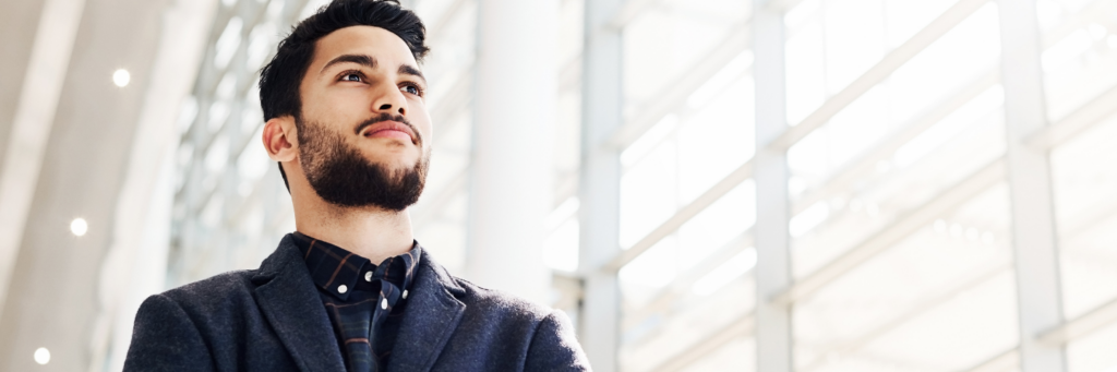 Low angle shot of a handsome young businessman standing alone with his arms crossed while in the office