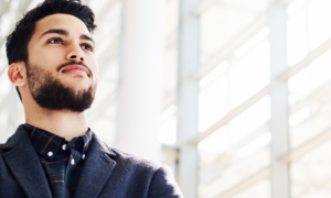 Low angle shot of a handsome young businessman standing alone with his arms crossed while in the office