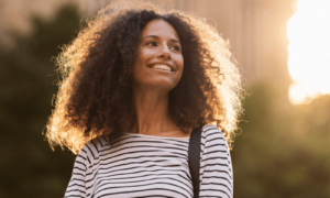 Happy empowered woman with long frizzy black hair in the sunshine