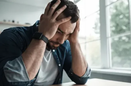 Distressed man sitting with his hands to his head