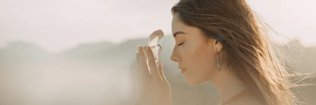 woman in misty mountains drawing energy from a crystal