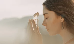 woman in misty mountains drawing energy from a crystal