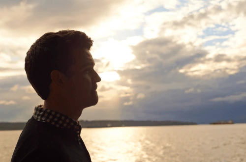 Young man reflecting about the future and life and death, by the ocean.