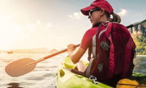 woman with blonde hair paddling on a kayak in the early morning