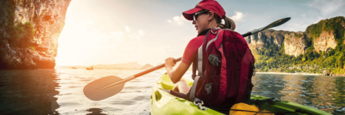 woman with blonde hair paddling on a kayak in the early morning